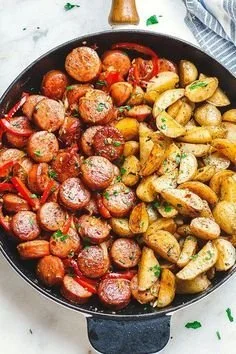 Smoked sausage and potato skillet garnished with herbs in a skillet dish.