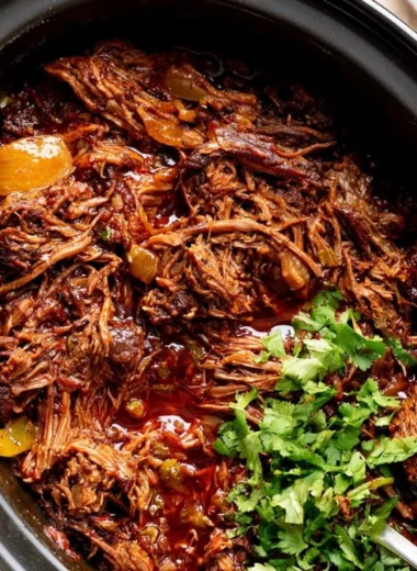 A bowl of cozy beef barbacoa served with tortillas and fresh toppings.