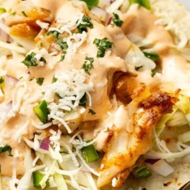 Plate of vibrant fish tacos topped with fresh cilantro and lime