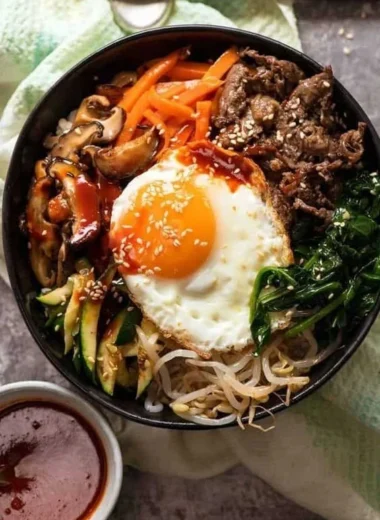 Korean Bibimbap served with colorful vegetables and a fried egg on top.