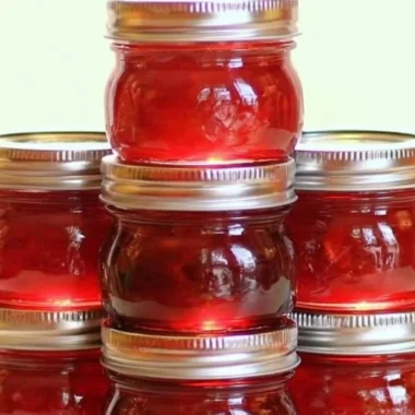 Jar of homemade rhubarb cinnamon jam on a wooden table with fresh rhubarb
