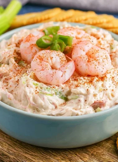 Creamy shrimp dip served in a bowl with crackers and garnished with herbs