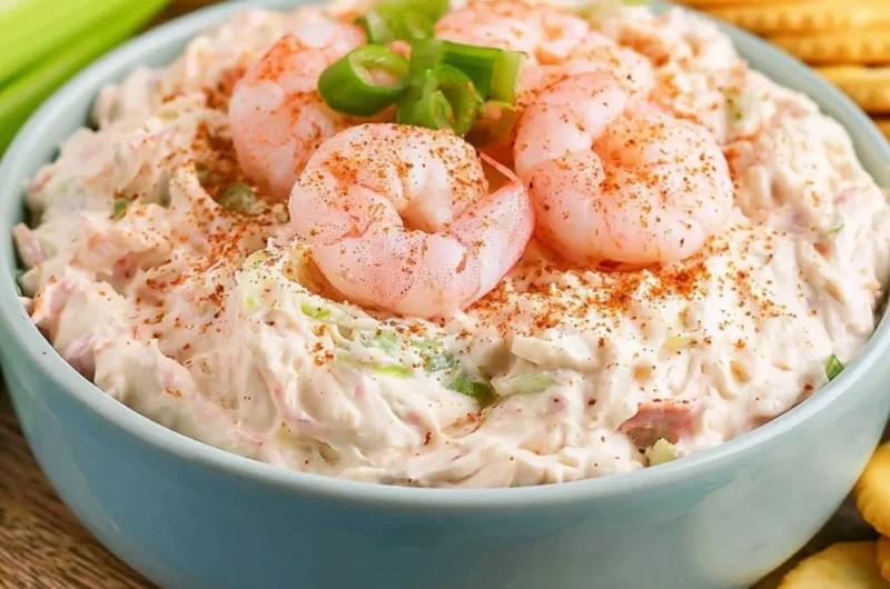 Creamy shrimp dip served in a bowl with crackers and garnished with herbs