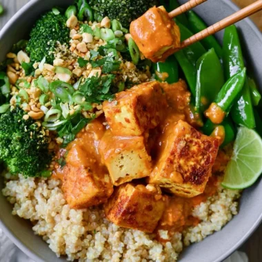 Cozy Thai peanut tofu quinoa bowl with fresh vegetables and peanut sauce.