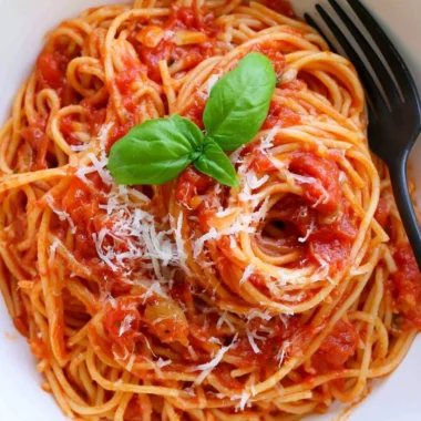 Cozy pasta tomato dish garnished with fresh herbs and cheese