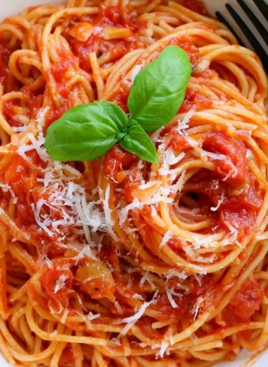 Cozy pasta tomato dish garnished with fresh herbs and cheese