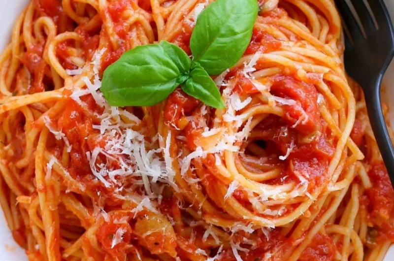 Cozy pasta tomato dish garnished with fresh herbs and cheese