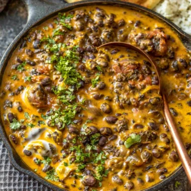 Creamy black bean curry served in a bowl with fresh herbs on top