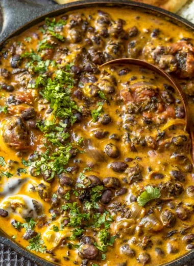 Creamy black bean curry served in a bowl with fresh herbs on top