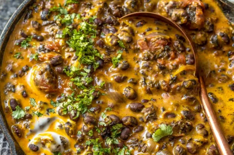 Creamy black bean curry served in a bowl with fresh herbs on top