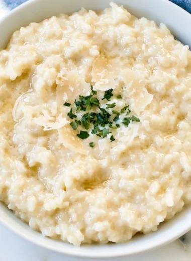 A bowl of creamy Parmesan Risotto garnished with herbs and Parmesan cheese