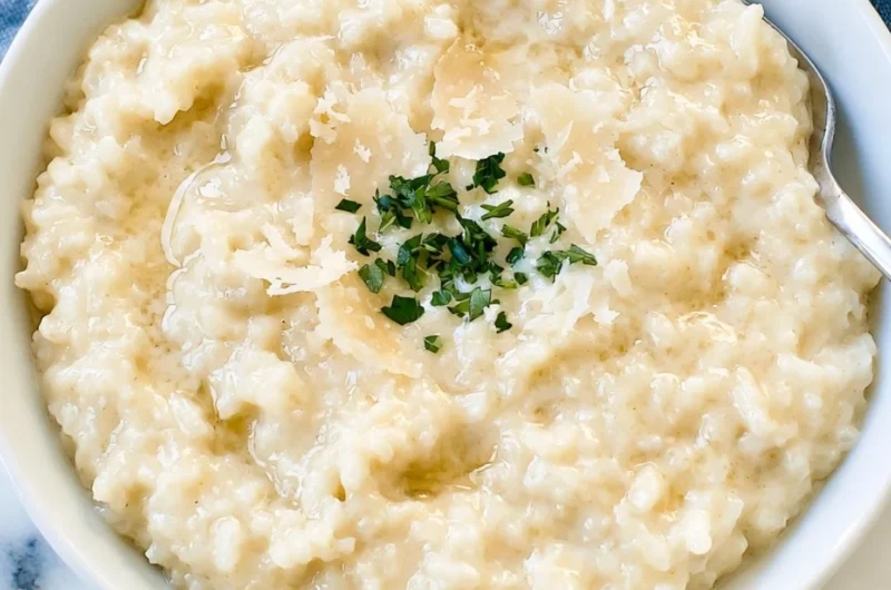 A bowl of creamy Parmesan Risotto garnished with herbs and Parmesan cheese