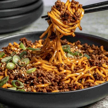 Bowl of easy Mongolian Ground Beef Noodles garnished with vegetables