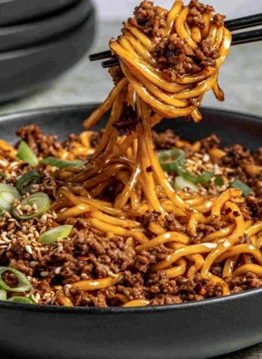 Bowl of easy Mongolian Ground Beef Noodles garnished with vegetables