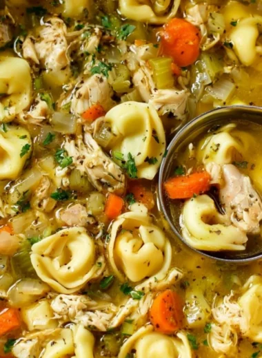 Bowl of cozy chicken tortellini soup garnished with herbs