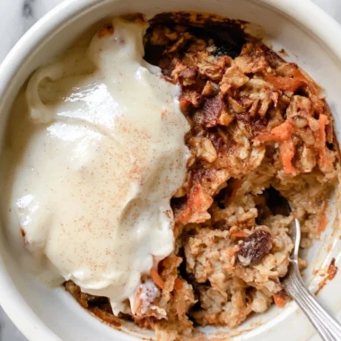 Delicious Carrot Cake Baked Oatmeal served in a bowl with oats and carrot shavings.