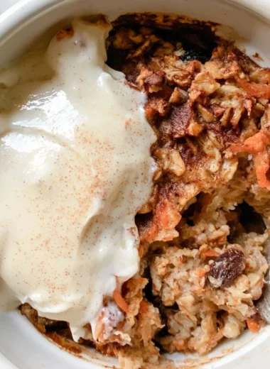 Delicious Carrot Cake Baked Oatmeal served in a bowl with oats and carrot shavings.