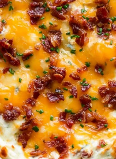 Cream cheese dip topped with bacon and cheddar cheese in a serving bowl
