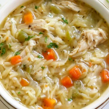 Bowl of Lemon Chicken Orzo Soup garnished with fresh herbs
