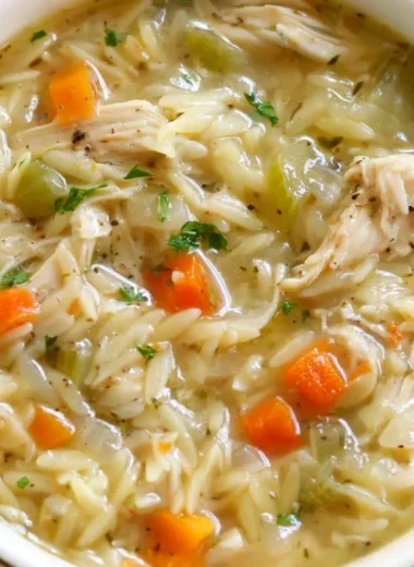 Bowl of Lemon Chicken Orzo Soup garnished with fresh herbs