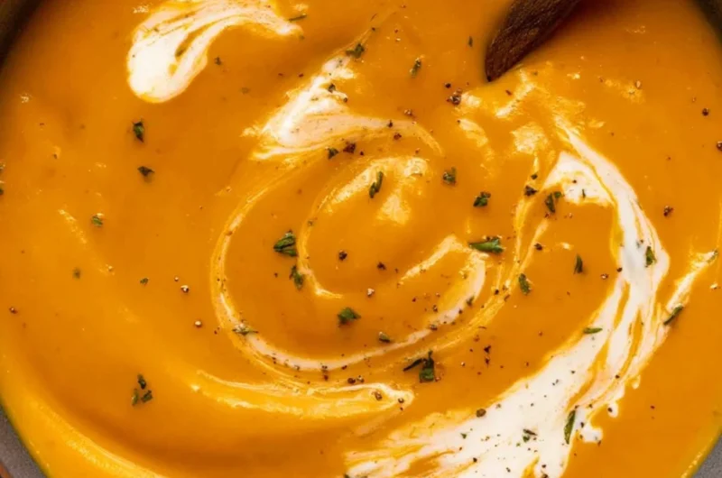 Bowl of maple roasted sweet potato carrot soup garnished with herbs